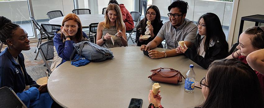 优秀生们围坐在学生中心的桌子边聊天边吃冰淇淋