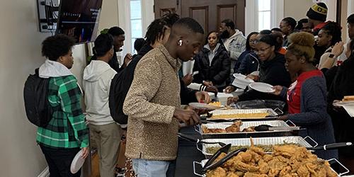 Black Alumni Society Community Engagement Lunch with members getting food in buffet line.